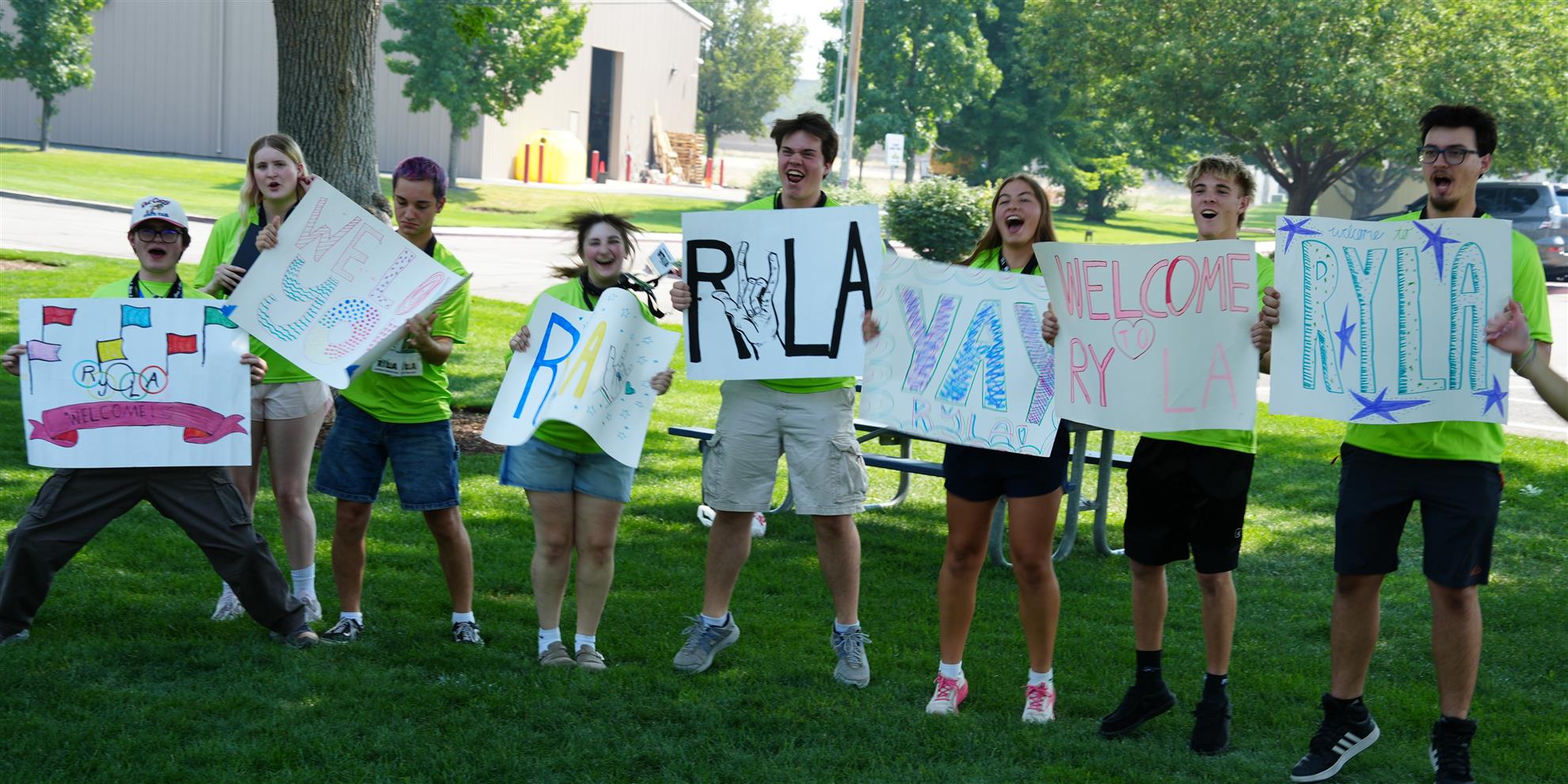 Young leaders holding welcome signs at a RYLA gathering