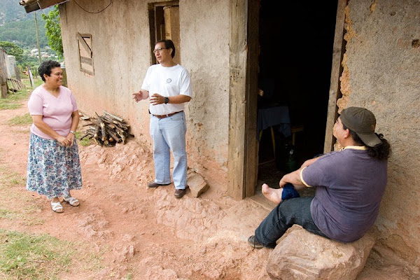 Three adults talk together outside a home.