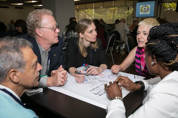 Participants share a discussion around a table at a Rotary symposium.