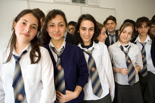 Students in school uniforms gather together in a school corridor.
