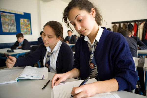Two students in school uniforms work together on a classroom assignment.